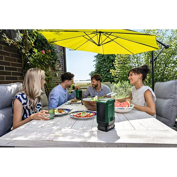 Bosch Power for All 18V Bluetooth-Lautsprecher Universal 18V-1 - 18 V, Ohne Akku - Grünes und schwarzes Bosch-Gerät auf einem Gartentisch während eines Treffens.