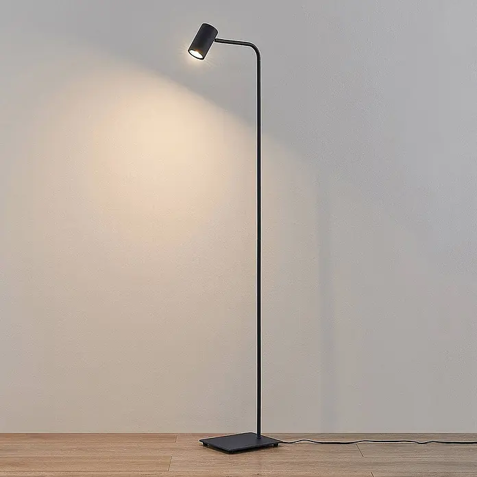Lindby Stehleuchte Sanad - schwarz, schwarz, GU10 - Schwarze, minimalistische Stehleuchte mit verstellbarem Spotkopf, beleuchtet eine Wand.