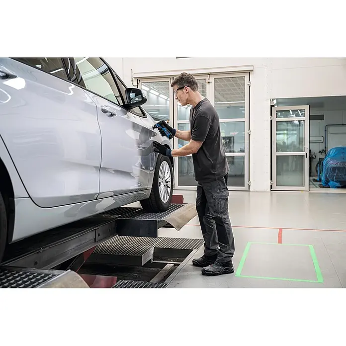Bosch Professional Akku-Schwingschleifer GSS 12V-32 - 12 V, Anzahl Akkus: Ohne Akku, 6.000 U/min - 16.000 U/min - Mann benutzt ein schwarz-blaues Akku-Rotationswerkzeug an einer Autokarosserie.