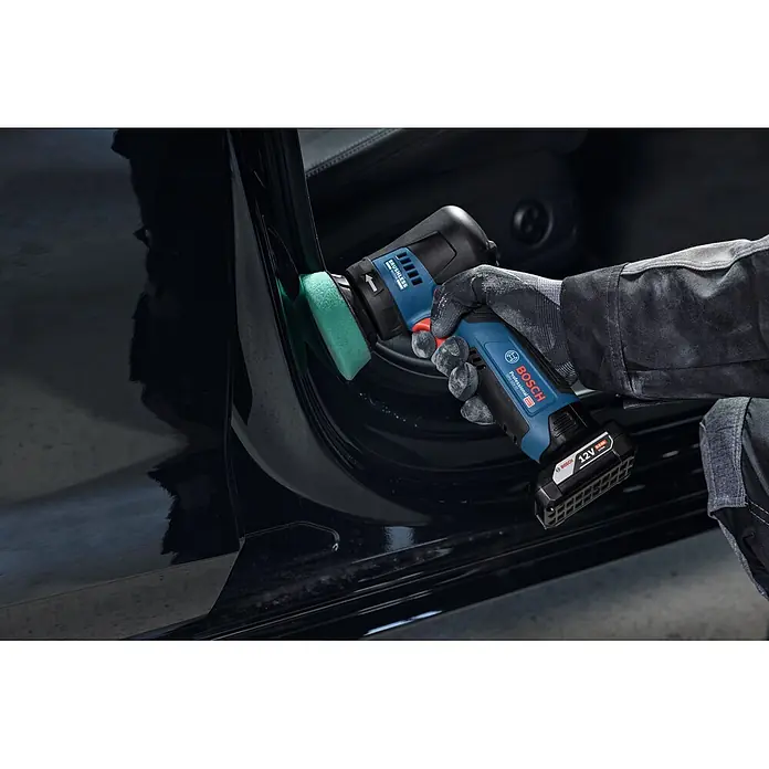 Bosch Professional Akku-Exzenterschleifer GEX 12V-77 - 12 V, Ohne Akku, Durchmesser Schleifteller: 77 mm - Eine behandschuhte Hand reinigt mit einem blau-schwarzen Bosch Professional Elektrowerkzeug und grünem Schrubber einen Autotürrahmen.