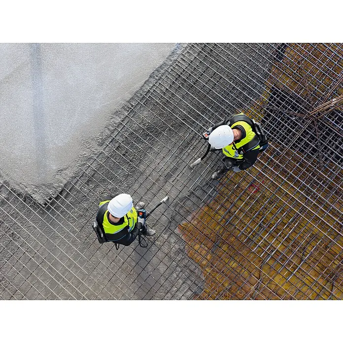 Bosch Professional Tragesystem Akku-Betonrüttler-System GBP100 - 335 x 139 x 540 mm - Zwei Bauarbeiter in Warnwesten und Schutzhelmen gießen Beton über eine Bewehrungsmatte auf einer Baustelle.
