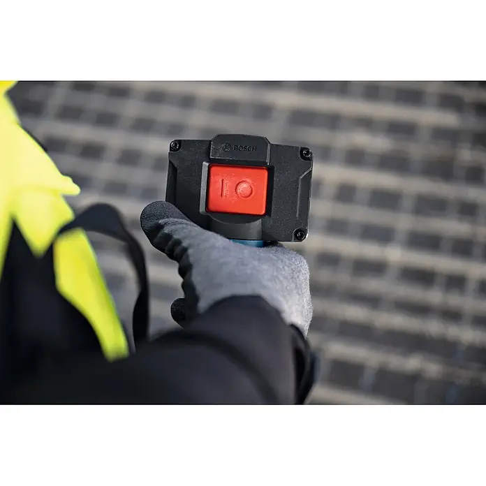 Bosch Professional Innenrüttler Akku-Betonrüttler-System GDI59-65D - Kabellänge: 1 m - Behandschuhte Hand bedient einen schwarzen Bosch-Steuerschalter mit großem rotem Ein/Aus-Knopf.