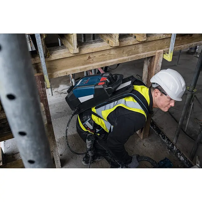 Bosch Professional Tragesystem Akku-Betonrüttler-System GBP100 - 335 x 139 x 540 mm - Bauarbeiter mit blau-schwarzem Bosch Rucksack-Stromsystem, an Werkzeug angeschlossen.