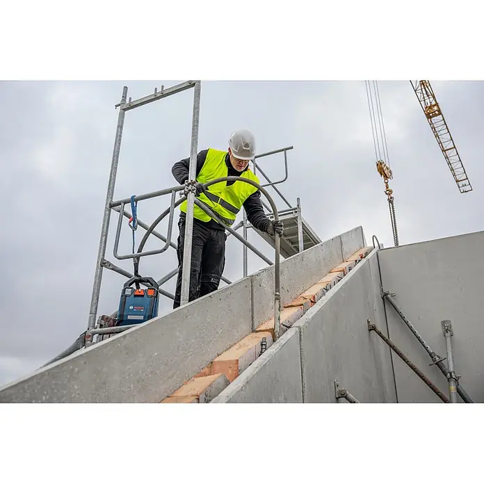 Bosch Professional Innenrüttler Akku-Betonrüttler-System GDI50-500 - Kabellänge: 5 m - Blauer Bosch Laser-Nivellier an einem Gerüst auf einer Baustelle, mit einem Arbeiter in Warnweste in der Nähe.