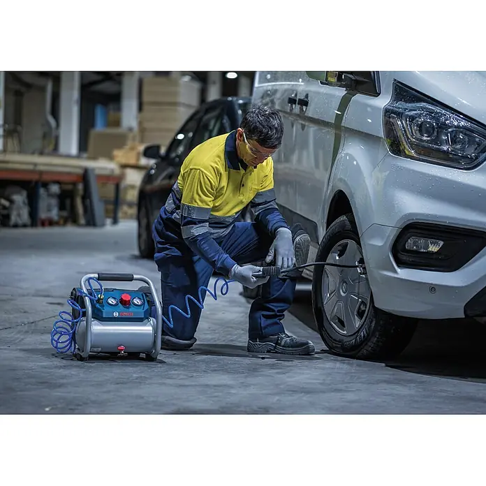 Bosch Professional AMPShare 18V Akku-Kompressor GKO18V-51 - 18 V, 8 bar - Blau-silberner BOSCH Kompressor wird von einem Mann zum Aufpumpen eines Reifens an einem weißen Van verwendet.