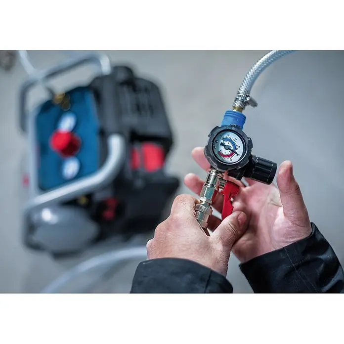 Bosch Professional AMPShare 18V Akku-Kompressor GKO18V-51 - 18 V, 8 bar - Hände justieren ein Manometer mit Schlauch und Schnellkupplung, verbunden mit einem Kompressor.