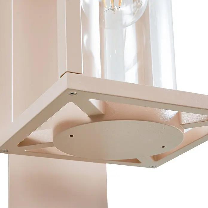 Lucande Außenwandleuchte Ferda - creme / amber, creme / amber, IP44 - Nahaufnahme einer sandfarbenen Metall-Leuchtenbasis mit Klarglas-Schirm und sichtbarer Glühfadenbirne.