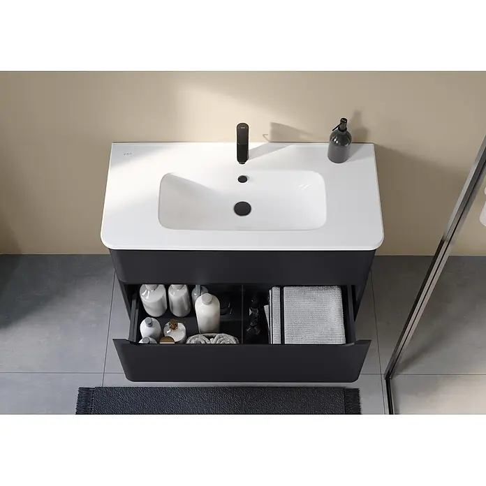VitrA Integra Round Badmöbel-Set - Gesamtbreite Badmöbel: 100 cm, Graphit, Matt - Moderne schwarze Badmöbel mit weißem Waschbecken, schwarzem Wasserhahn und geöffneter Schublade mit organisierten Toilettenartikeln und Handtüchern.