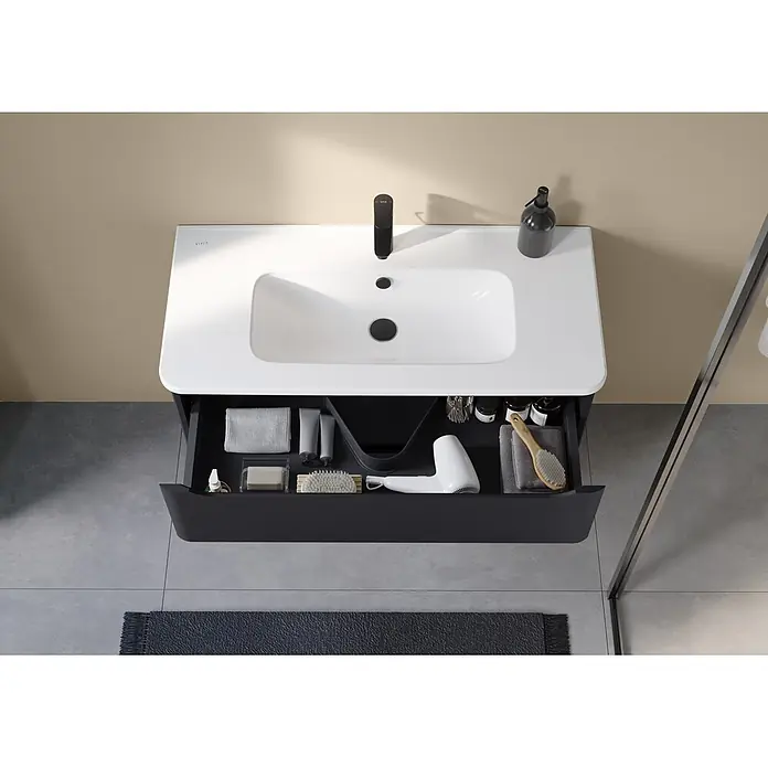 VitrA Integra Round Badmöbel-Set - Gesamtbreite Badmöbel: 100 cm, Graphit, Matt - Waschtisch mit weißem Becken, schwarzer Armatur und offener dunkelgrauer Schublade mit Pflegeprodukten und Föhn.