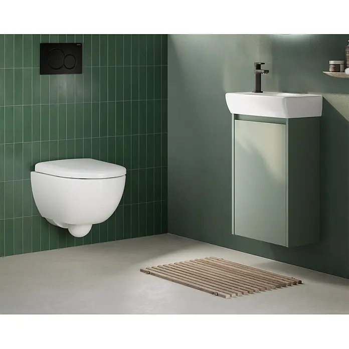 Geberit Renova Compact Wand-WC-Set - Spülrandlos, Ohne Spezialglasur, Spülform: Tief, WC Abgang: Waagerecht, Weiß - Modernes Bad mit weißem Wand-WC, schwarzer Spültaste und hellgrünem Waschtischunterschrank mit weißem Becken.