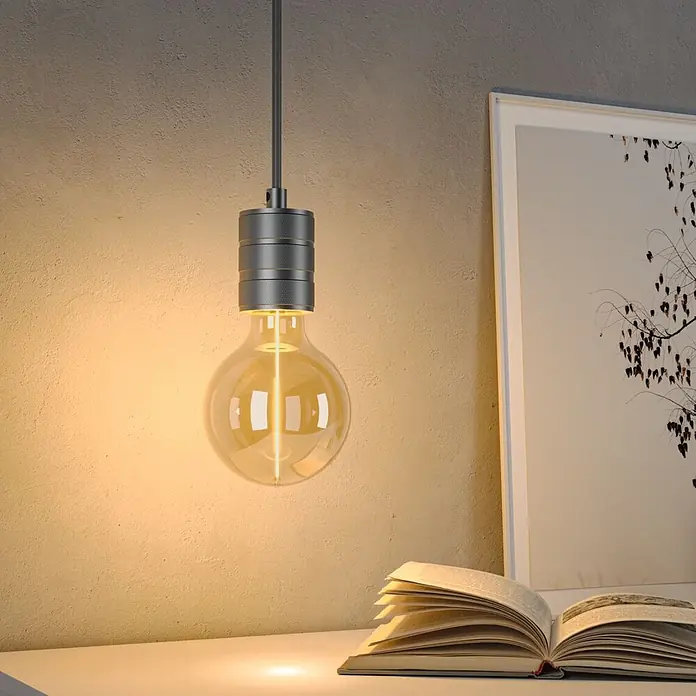 Paulmann LED-Lampe Floating G95 Gold - E27, Warmweiß, 140 lm, 2,8 W - Hängelampe mit grauem Metallfassung und großer, runder bernsteinfarbener LED-Glühbirne, beleuchtet ein Buch auf einem Tisch.