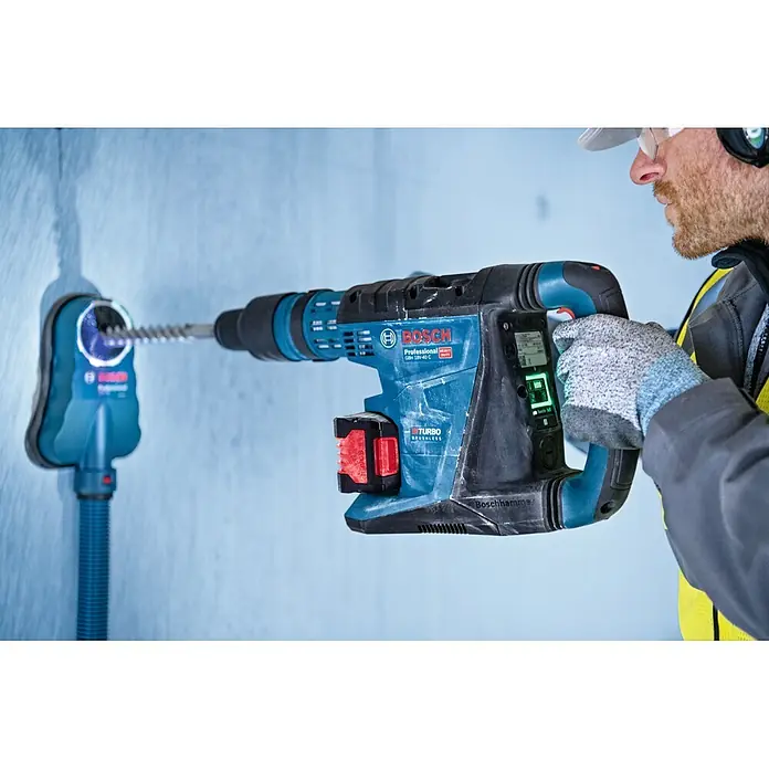 Bosch Professional AMPShare 18V Akku & Ladegerät Starter-Set Expert 2x EXBA18V-55 + GAL12V/18V-80 - 18 V, 2 Akkus, 5,5 Ah - Eine Person bohrt mit einem blau-schwarzen Bosch Bohrhammer und Staubabsaugung in eine Wand, Schutzausrüstung tragend.