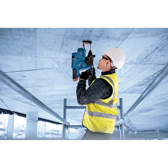 Bosch Professional AMPShare 18V Akku & Ladegerät 1X EXBA 18V-40, GAL 12V/18V - 18 V, 1 Akku, 4 Ah - Arbeiter nutzt blauen Akku-Bohrhammer mit Staubabsaugung, um in eine Betondecke zu bohren.