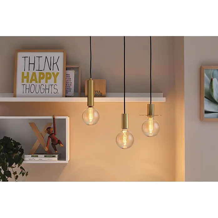 Paulmann LED-Lampe Inner Glow Arc - E27, Dimmbar, Warmweiß, 300 lm, 4,2 W - Drei moderne Messing-Pendelleuchten mit klaren Glühbirnen beleuchten ein Regal in einem warmen Raum.