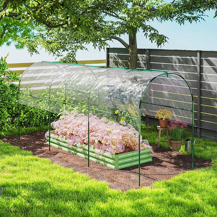 Outsunny Gewächshaus - Außenmaß inkl. Dachüberstand (B x T): 123 x 400 cm, Material Seitenwand: Kunststoff, 0,3 mm, Dunkelgrün - Minigewächshaus mit klarer Kunststoffabdeckung und grünem Rahmen über einem Hochbeet mit rosa Blumen.