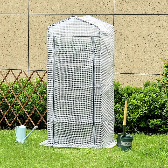 Outsunny Gewächshaus - 70 x 50 cm, Material Seitenwand: Kunststoff, 0,3 mm, Grün - Ein hohes, weißes Mini-Gewächshaus mit Gittermuster und Spitzdach steht auf Gras im Garten, mit Gartengeräten daneben.