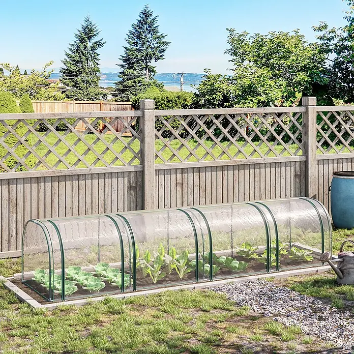 Outsunny Gewächshaus - 395 x 100 cm, Material Seitenwand: Kunststoff, 0,3 mm, Grün - Transparenter Gewächshaustunnel mit grünen Rahmen über einem Beet junger Pflanzen im Garten.