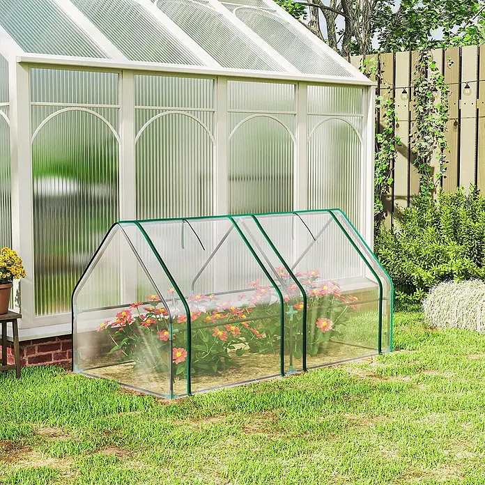 Furnicato Gewächshaus - 90 x 180 cm, Material Seitenwand: Stahl, 14 mm, silber - Transparentes Mini-Gewächshaus mit grünem Rand, schützt rote Blumen auf einem Rasen.