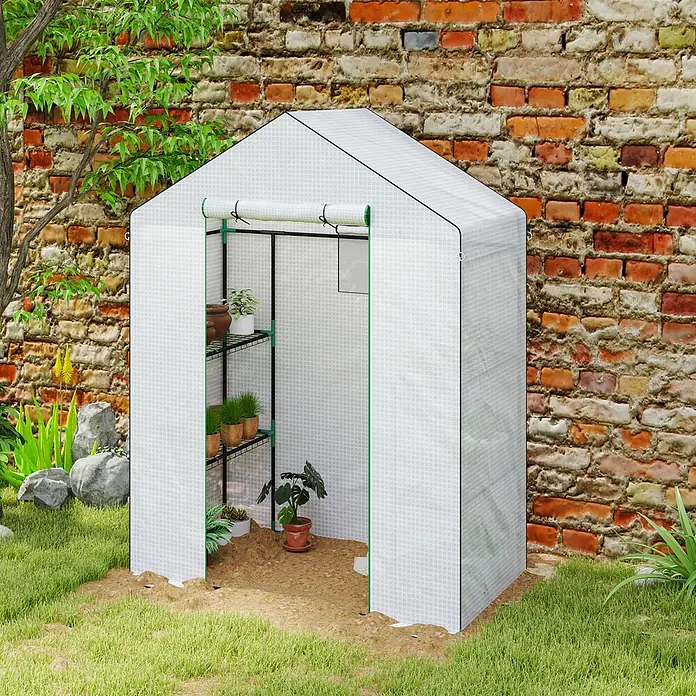 Furnicato Gewächshaus - 74 x 143 cm, Material Seitenwand: Kunststoff, 14 mm, weiß - Weißes begehbares Gewächshaus mit grünem Rahmen, gefüllt mit Topfpflanzen auf Regalen, im Garten platziert.