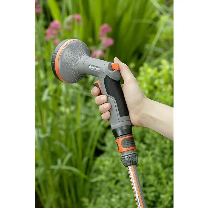 Gardena Comfort Brause - Anzahl Sprühformen: 2 Stk., Metall/Kunststoff, Geeignet für: Pflanzreihenbewässerung - Eine Hand hält eine Gardena Mehrzweck-Brause mit orangenen Akzenten vor einem grünen Hintergrund. Ideal für Gartenbewässerung.