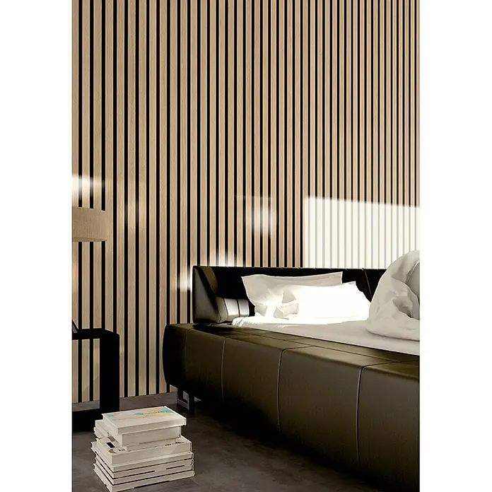 acous Akustikpaneel Economico - Eiche Hellbraun /schwarzer Filz, 2.400 x 380 x 16,5 mm - Helle vertikale Holzlattenpaneele mit dunklen Zwischenräumen, hinter einem Bett in einem modernen Schlafzimmer.