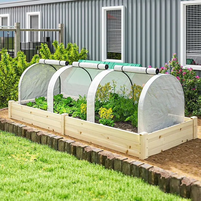 Furnicato Gewächshaus - Außenmaß inkl. Dachüberstand (B x T): 100 x 295 cm, Material Seitenwand: Stahl, 14 mm, weiß - Hölzernes Hochbeet mit zwei Bogenabdeckungen, gefüllt mit Pflanzen und gelben Blumen, in Gartenumgebung.