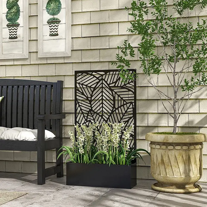 Outsunny Hochbeet - 61 x 23 x 113 cm, Metall, Schwarz - Schwarzer Metall-Sichtschutz mit Blattschnittmuster, integriert in ein schwarzes rechteckiges Pflanzgefäß mit weißen Blumen auf einer Terrasse.