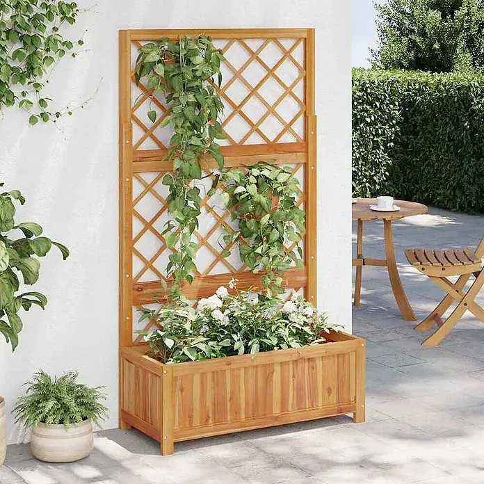 Furnicato Hochbeet Akazien-Massivholz geölt - 85 x 38 x 150 cm, Holz, Braun - Hölzernes Pflanzgefäß mit Spalier für Kletterpflanzen und weiße Blumen, auf einer Terrasse.