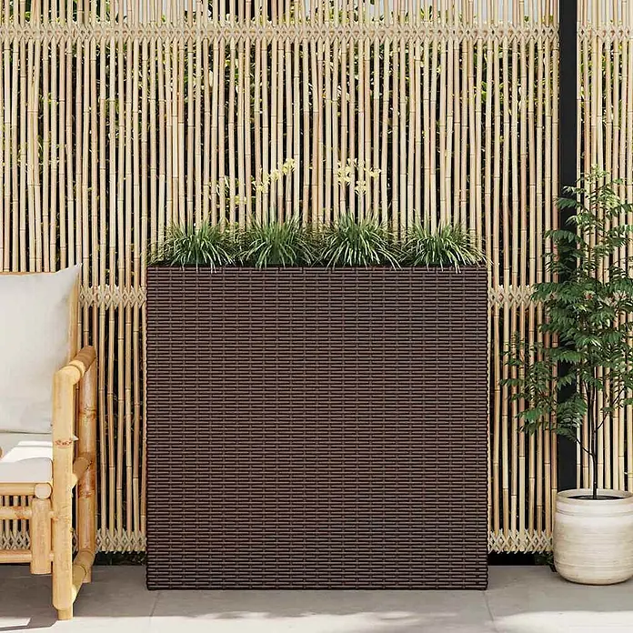 Furnicato Hochbeet Poly Rattan - 79 x 22 x 76 cm, Kunststoff, Braun - Dunkelbrauner Rattan-Pflanzkübel mit grünen Pflanzen, im Freien vor einem Bambuszaun und einem Stuhl.
