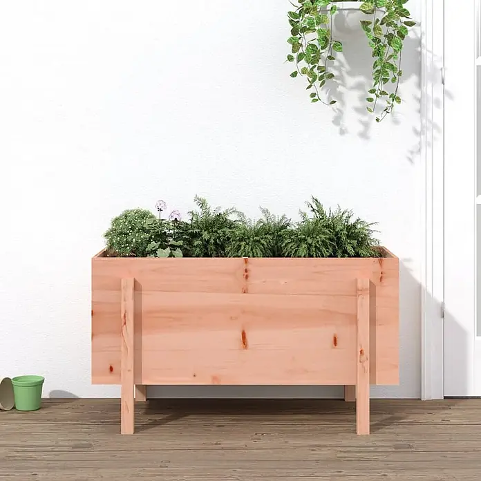 Furnicato Hochbeet - 50 x 101 x 57 cm, Holz, Natürliches Douglasie - Hölzerner Pflanzkasten auf Beinen, gefüllt mit diversen Grünpflanzen und rosa Blüten.