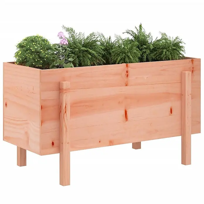 Furnicato Hochbeet - 50 x 101 x 57 cm, Holz, Natürliches Douglasie - Heller Holz-Pflanzkasten auf Beinen, gefüllt mit verschiedenen Grünpflanzen und rosa Blüten.