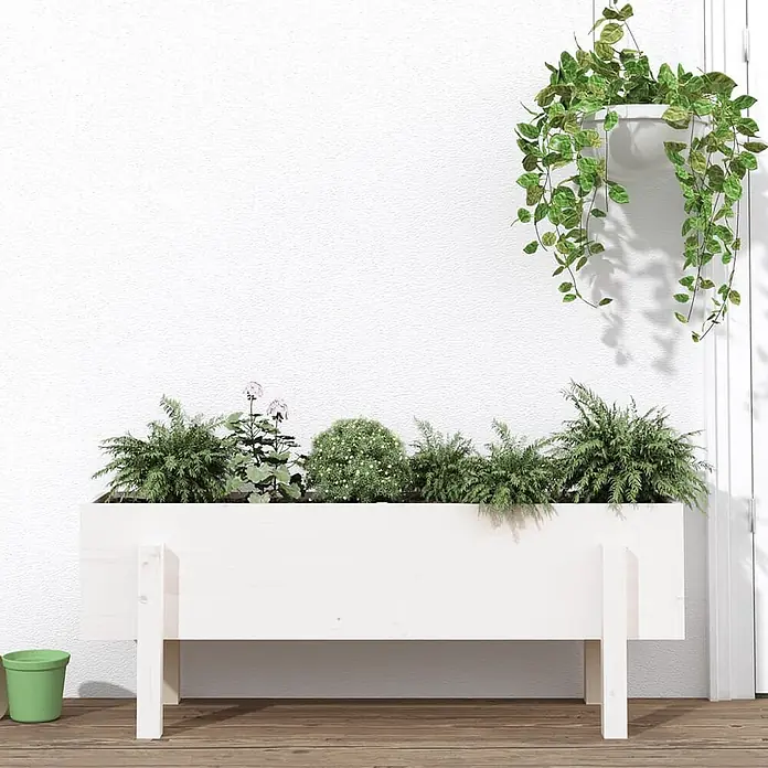 Furnicato Hochbeet - 30 x 101 x 38 cm, Holz, Weiße Kiefer - Weißer Pflanzkasten aus Holz, gefüllt mit üppigen Grünpflanzen und zarten rosa Blumen, auf einem Holzuntergrund.