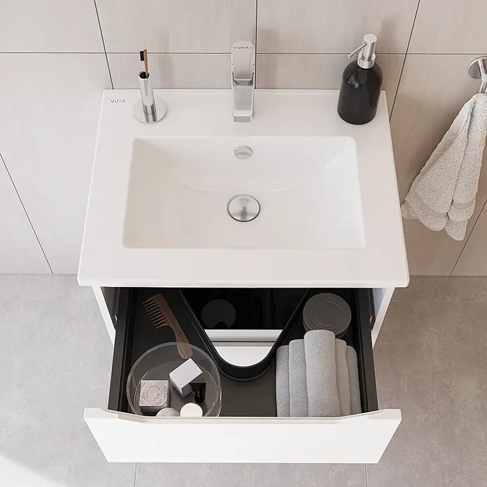 VitrA Integra Square Badmöbel-Set - Gesamtbreite Badmöbel: 60 cm, Weiß, Matt - Weißer Keramik-Waschtisch mit Chromarmatur. Die geöffnete Schublade zeigt schwarze Einsätze, graue Handtücher, einen Holzkamm und Toilettenartikel.