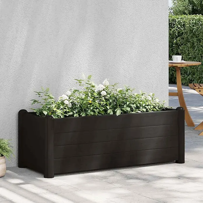 Furnicato Hochbeet - 100 x 43 x 35 cm, Kunststoff, Anthrazit - Dunkelbrauner rechteckiger Pflanzkasten mit weißen und gelben Blumen auf einer Terrasse.