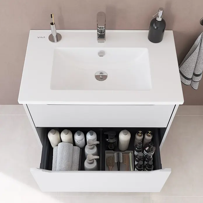 VitrA Integra Square Badmöbel-Set - Gesamtbreite Badmöbel: 80 cm, Hellgrau, Matt - Weißer VitrA Badezimmer-Waschtisch mit integriertem Waschbecken, Chromarmatur und geöffneter Schublade voller Toilettenartikel und Bürsten.