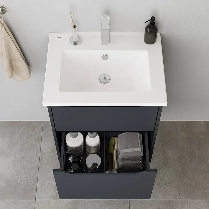 VitrA Integra Square Badmöbel-Set - Gesamtbreite Badmöbel: 60 cm, Graphit, Matt - Dunkelgrauer Badunterschrank mit weißem Keramikwaschbecken und geöffneter Schublade, die organisierte Toilettenartikel und Handtücher zeigt.