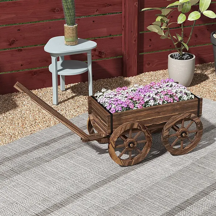 Furnicato Hochbeet - 120 x 41 x 54 cm, Holz, Verkohlt - Dekorativer hölzerner Wagen-Pflanzkübel mit rosa und weißen Blumen, auf einem gestreiften Outdoor-Teppich im Garten.