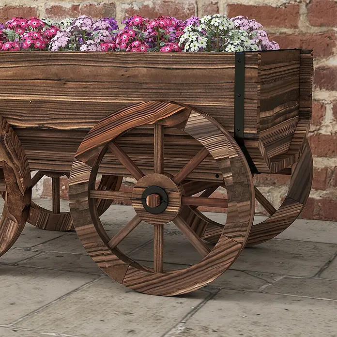 Furnicato Hochbeet - 120 x 41 x 54 cm, Holz, Verkohlt - Dunkelbrauner hölzerner Wagen-Pflanzkübel mit großen Rädern, gefüllt mit leuchtend rosa, lila und weißen Blumen.