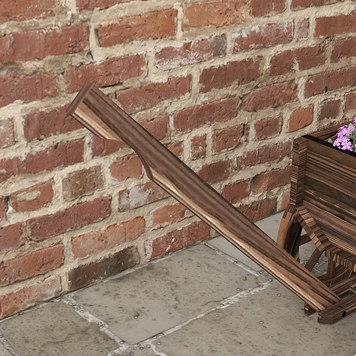 Furnicato Hochbeet - 120 x 41 x 54 cm, Holz, Verkohlt - Hölzerner Dekowagen mit rosa Blumen, an eine Ziegelwand gelehnt auf gepflastertem Untergrund.