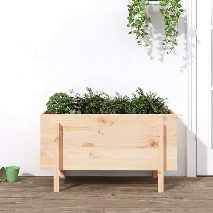 Furnicato Hochbeet - 50 x 101 x 57 cm, Holz, Natürliche Kiefer - Pflanzkasten aus hellem Holz, gefüllt mit Grünpflanzen und kleinen rosa Blüten, auf Holzterrasse stehend.
