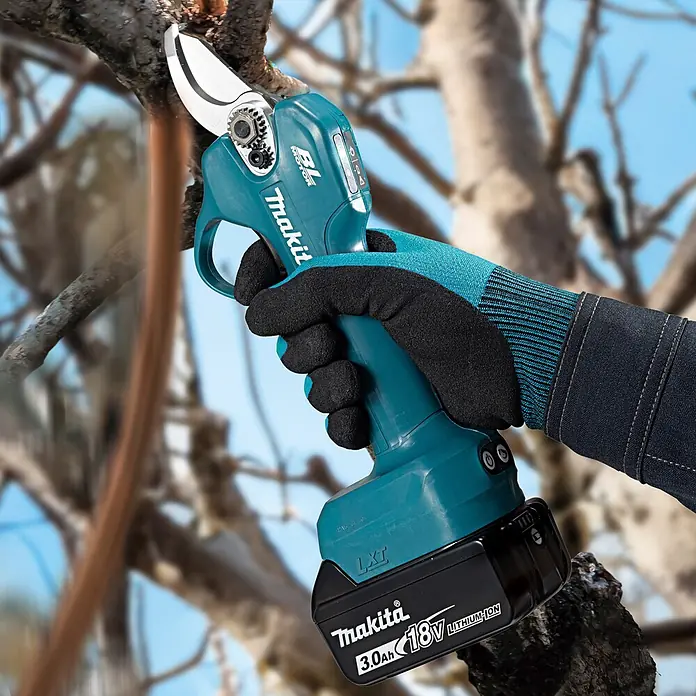 Makita LXT 18V Akku-Astschere DUP181Z - 18 V, Ohne Akku, Max. Aststärke: 30 mm - Eine behandschuhte Hand verwendet eine türkis-schwarze Makita Akku-Astschere, um einen Ast zu schneiden.