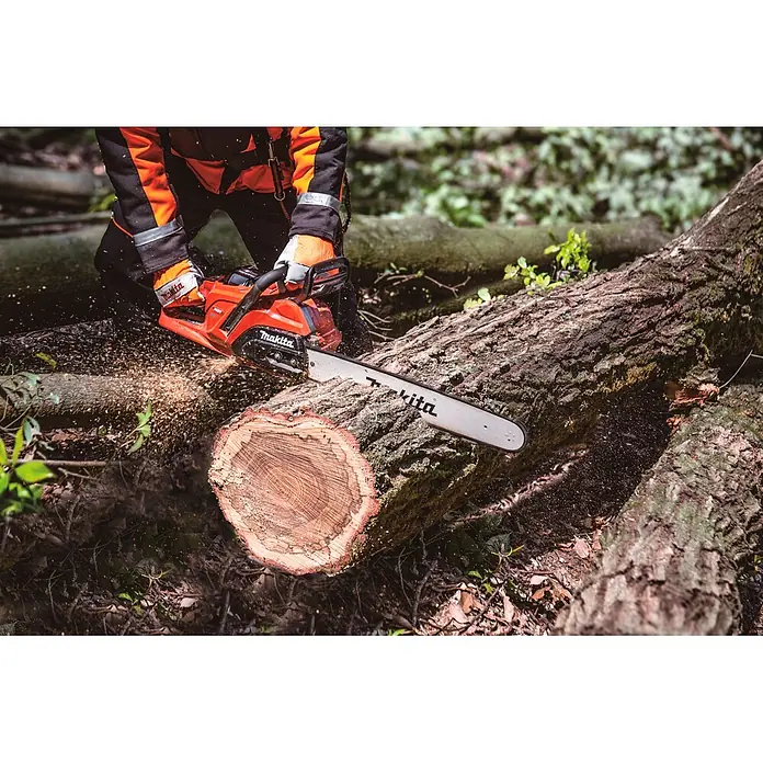 Makita XGT 40V max. Akku-Kettensäge UC030GZ03 - 40 V, Ohne Akku, Schwertlänge: 50 cm - Orange Makita Kettensäge sägt Baumstamm, bedient von Person in Schutzkleidung, Sägespäne fliegen.