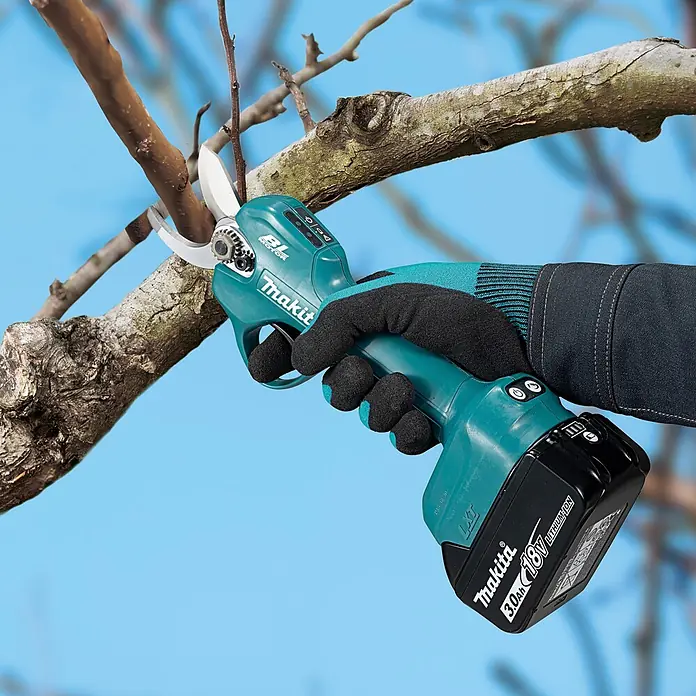 Makita LXT 18V Akku-Astschere DUP181Z - 18 V, Ohne Akku, Max. Aststärke: 30 mm - Türkis-schwarze Makita Astschere mit 18V-Akku, von behandschuhter Hand gehalten, schneidet einen Ast.