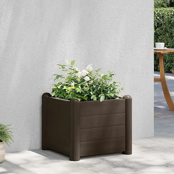 Furnicato Hochbeet - 43 x 43 x 35 cm, Kunststoff, Mokka - Dunkelbrauner quadratischer Blumenkasten mit Lattenseiten und abgerundeten Eckpfosten, gefüllt mit weißen und grünen Pflanzen, auf einer Terrasse.