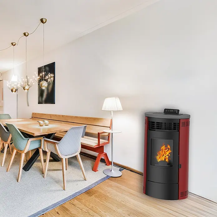 Sannover Pelletofen Flavia 15 kW Bordeaux - 13,8 kW, Raumheizvermögen: 300 m³, 2,6 kg/h, Farbe Verkleidung: Bordeauxrot - Roter und schwarzer Pelletofen heizt ein modernes Esszimmer mit sichtbarer Flamme durch die Glastür.