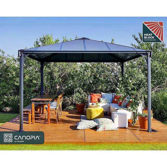Palram – Canopia Pérgola estándar Palermo - An x Pr: 360 x 360 cm, Material del armazón: Aluminio, Gris - Cenador gris oscuro con techo poligonal que bloquea el calor, protegiendo un área de comedor y lounge exterior en una terraza de madera.