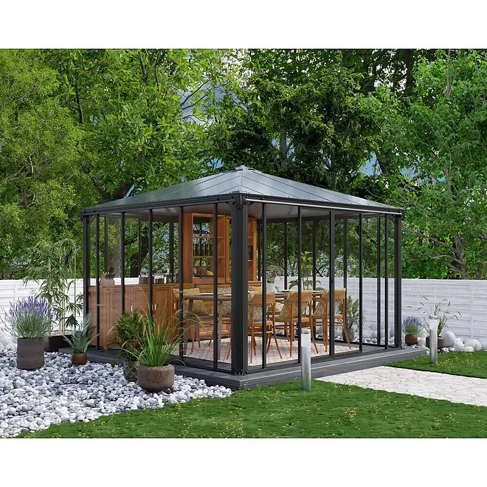 Palram – Canopia Pérgola de jardín cerrado Ledro - An x Pr: 360 x 360 cm, Color del armazón: Antracita, Aluminio - Un moderno pabellón de jardín de cristal y metal negro con comedor, rodeado de exuberante vegetación y un sendero de piedra.