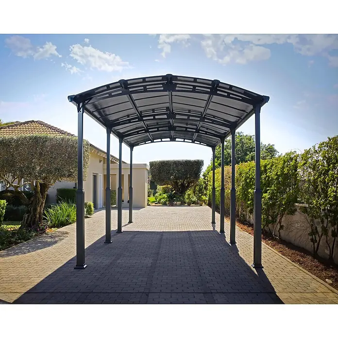 Palram – Canopia Carport Alpine - Medidas ext. (An x Pr): 3,59 x 8,63 m, Carport individual, Antracita - Cochera gris oscuro con techo curvo, que ofrece refugio en una entrada pavimentada frente a una casa.
