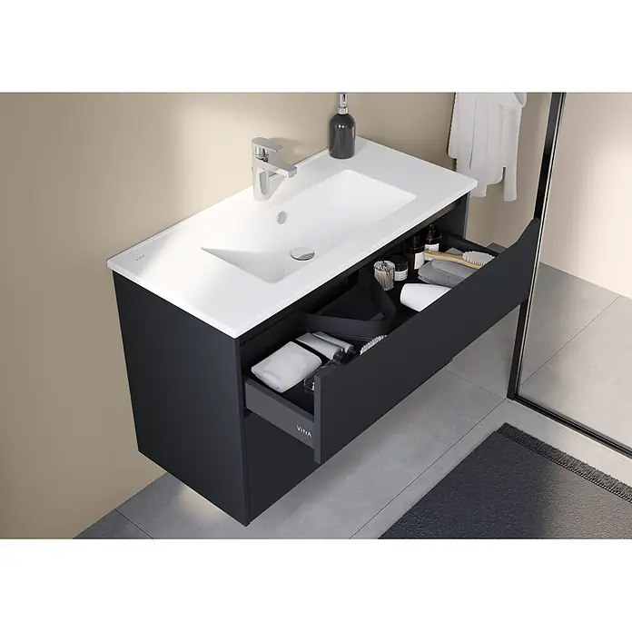 VitrA Integra Square Badmöbel-Set - Gesamtbreite Badmöbel: 100 cm, Graphit, Matt - Dunkelgrauer wandhängender Badschrank mit integriertem weißen Waschbecken, Chromarmatur und geöffneter Schublade mit Toilettenartikeln.
