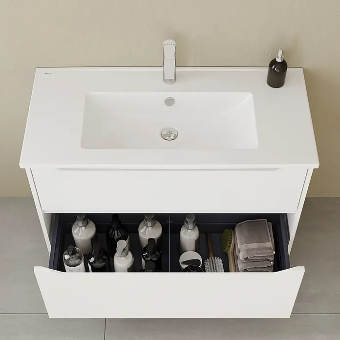VitrA Integra Square Badmöbel-Set - Gesamtbreite Badmöbel: 100 cm, Weiß, Matt - Weißer Badunterschrank mit integriertem Waschbecken und offener Schublade, die Toilettenartikel und Handtücher zeigt.